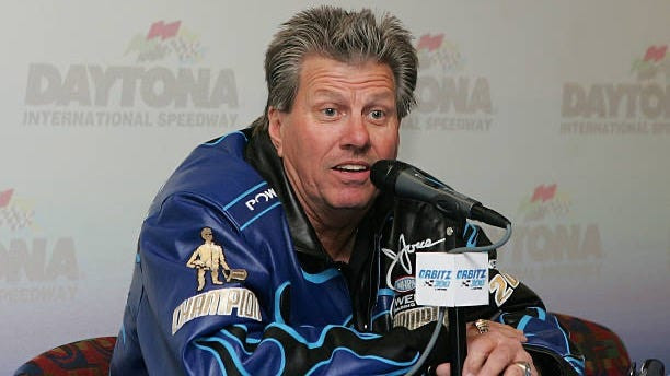 John Force waving to fans, signaling recovery progress after the 2024 wreck