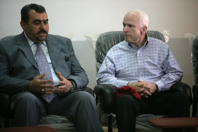 U.S. Senator John McCain engages in a discussion with the Governor of Al Anbar, Iraq, Mamoun Sami Rasheed Al Awani, during his visit to Haditha, Iraq, on March 16, 2008. McCain's visit underscored his deep interest in understanding the ground realities of the Iraq War and the perspectives of local leaders. Courtesy photo