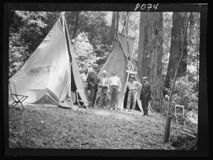 Black and white photograph of Bohemian Club members camping in a forest.