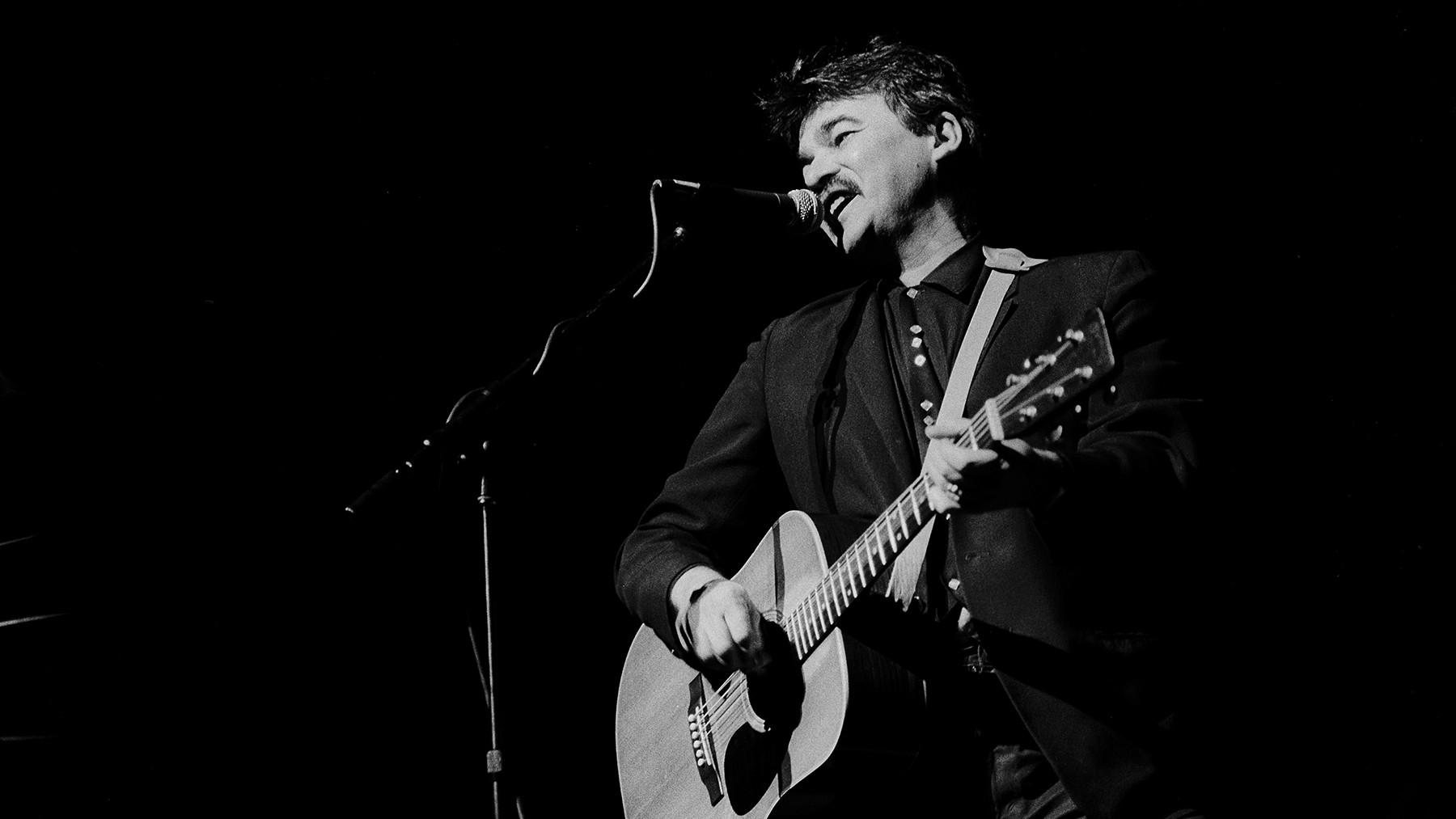 John Prine in a playful pose, reflecting the lighthearted and humorous nature of &quot;Let's Talk Dirty in Hawaiian&quot;.