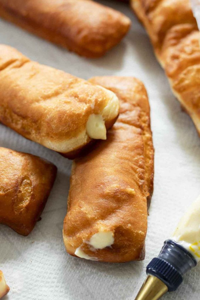 Creamy custard filling being piped into a Long John Donut.