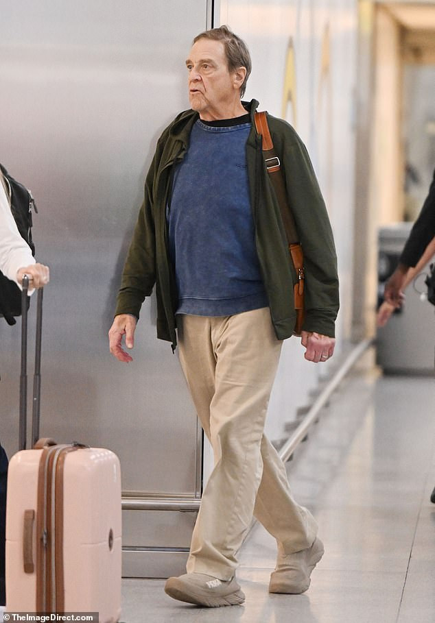 John Goodman's dedication to fitness is evident as he sports a dark green sweatshirt, khaki pants, and Hoka sneakers, showcasing his commitment to a healthy lifestyle.