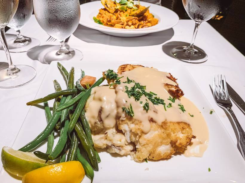 Fish with white cream sauce and green beans served over white tablecloth at Morgan