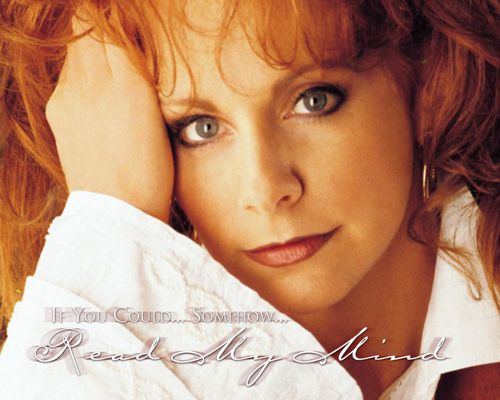 Reba McEntire performing onstage, microphone in hand, at a concert